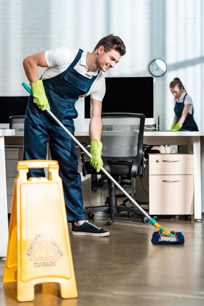 stock - Prime Cleaning Services Office cleaners mopping and wiping desks with a caution sign in front